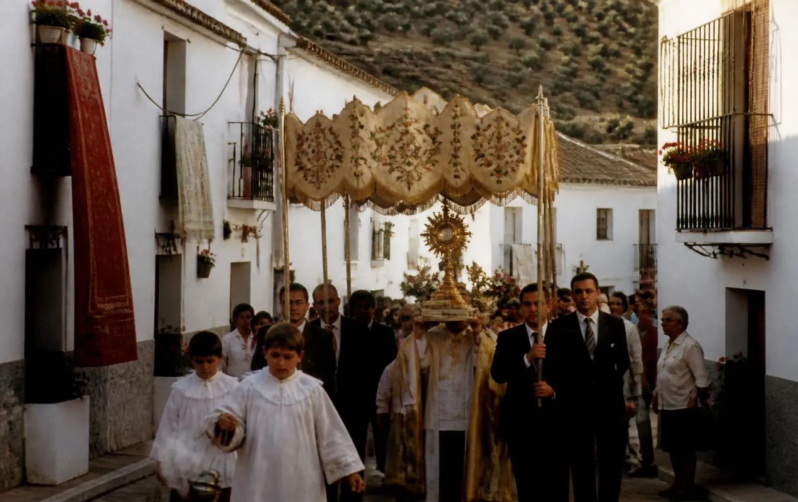 Procesión de Jesús Sacramentado bajo palio por una calle de Rus el domingo de la Fiesta de Mozos